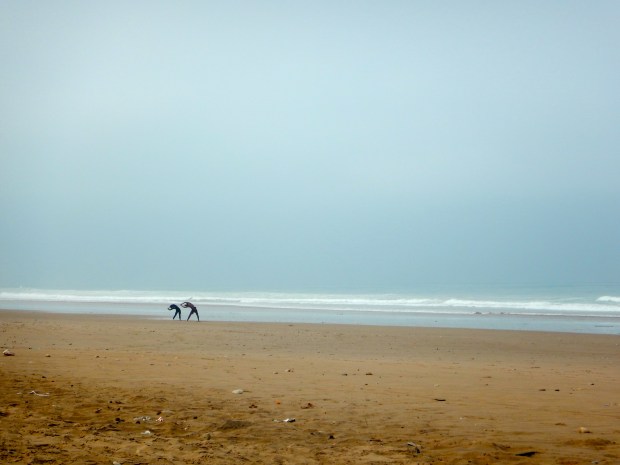 Some surfers doing some warm-up stretches on a deserted beach